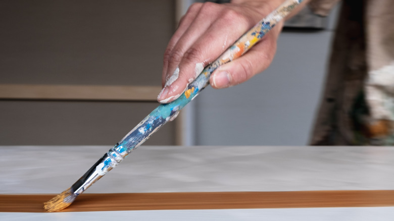 Close-up of person painting a white surface