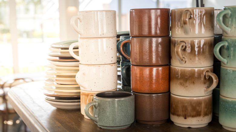 Stacks of mugs and plates sit on a table