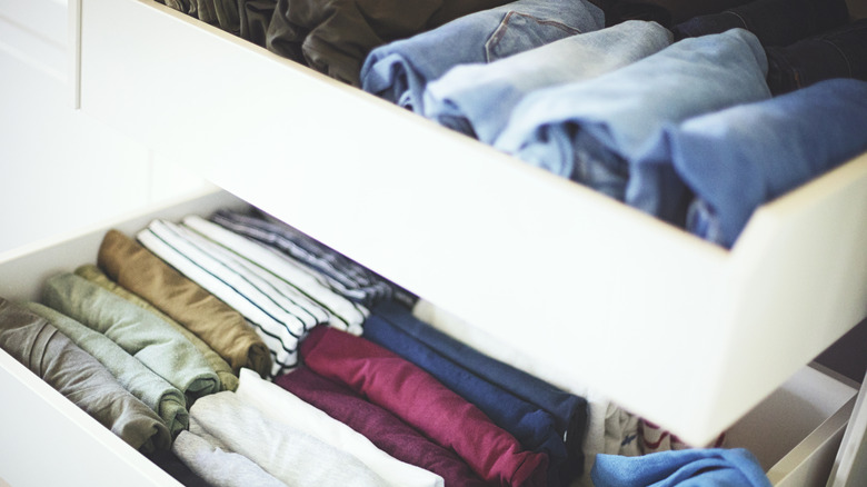 Neatly organized dresser drawers with folded t-shirts and blue jeans