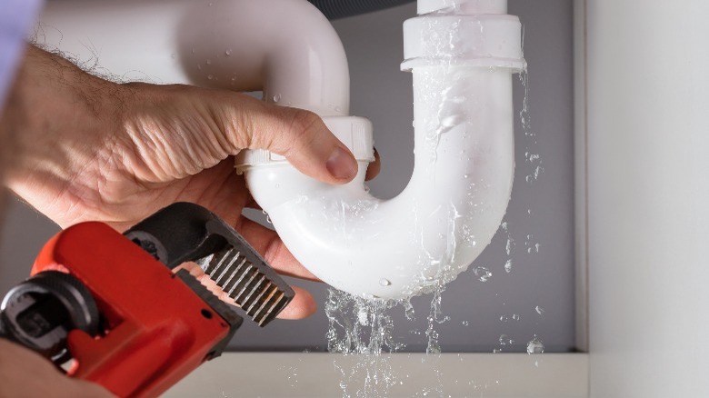 Fixing leaky white pipe with red wrench