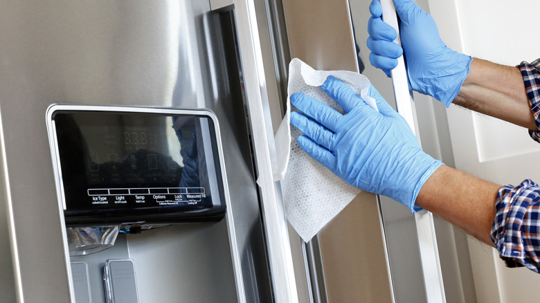 gloved hands cleaning fridge