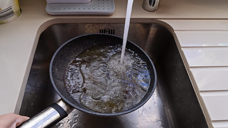 Person washing grease out of pan