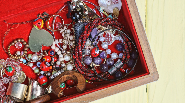 Disorganized bracelets and necklaces in a box on a table.