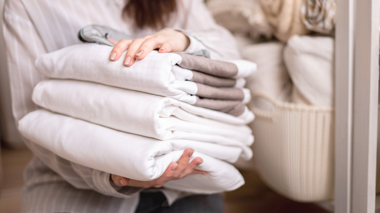 Person holding a stack of folded white sheets