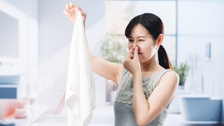 Woman smelling stinky towel