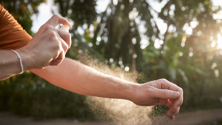 person spraying something on their arm