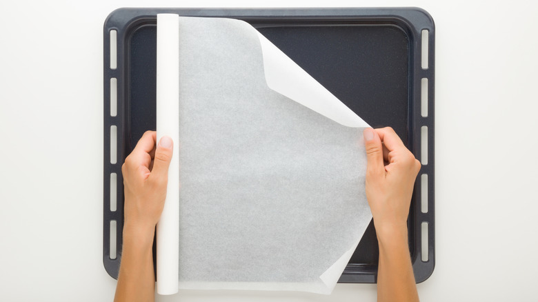 Person rolling white wax paper onto a pan