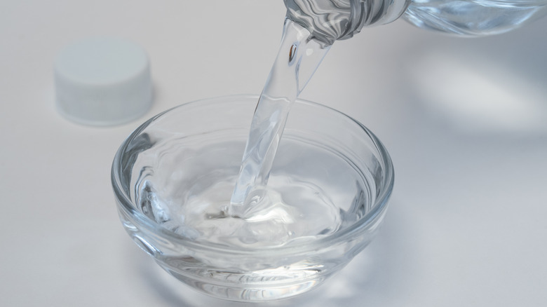 pouring white vinegar into container