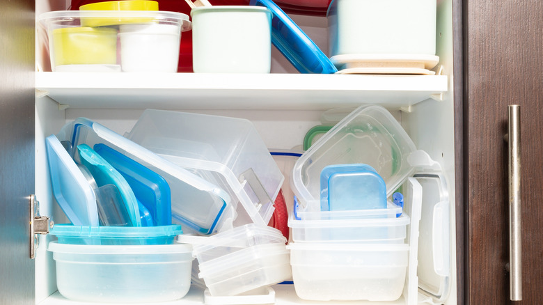 Cluttered kitchen cabinet with plastic containers and lids