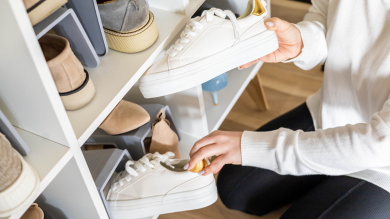 Person putting away their shoes in a cabinet