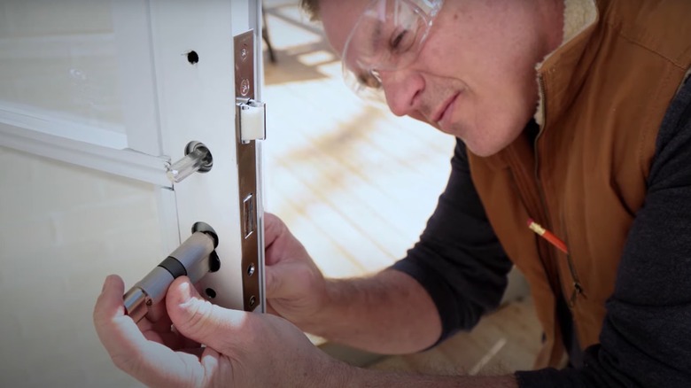 man installing storm door latch