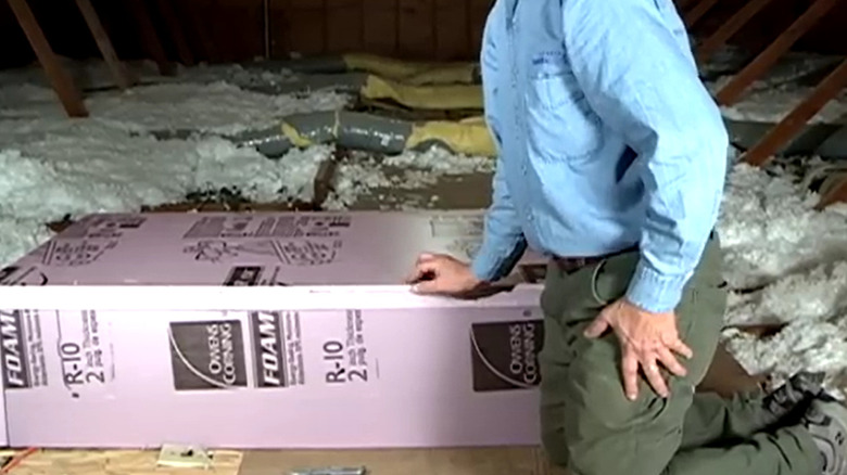 man next to completed insulation box for door in attic