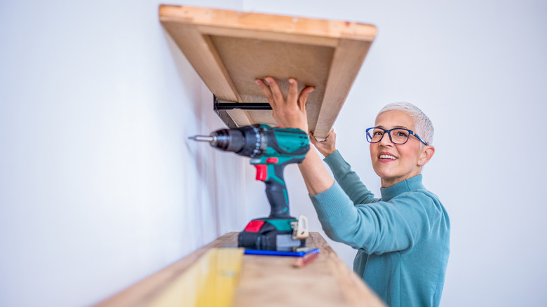 Woman reinforcing shelf with drill