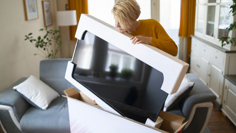 Woman removing TV from box in home