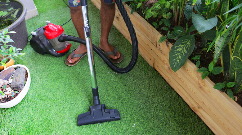 person vacuuming artificial turf