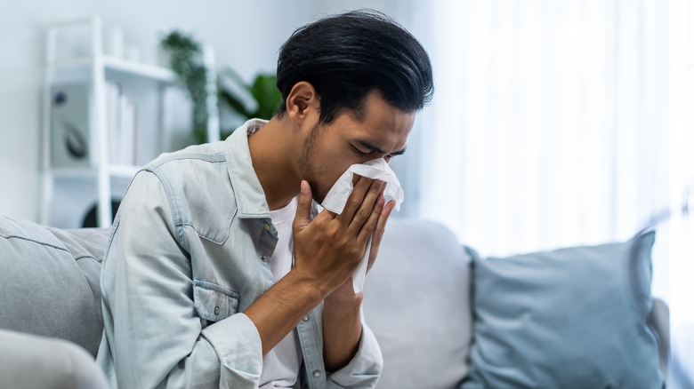 Man sneezing into tissue