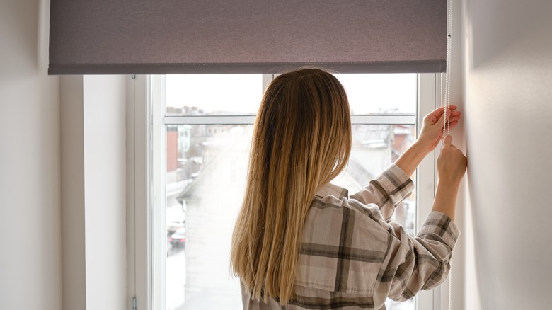 Person lowering window shade