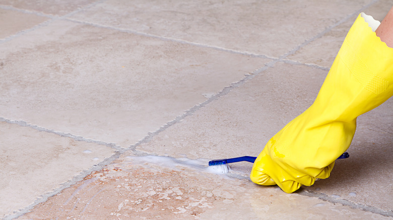 Someone using a toothbrush cleaning grout