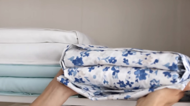 Person placing pillowcase bedding in closet