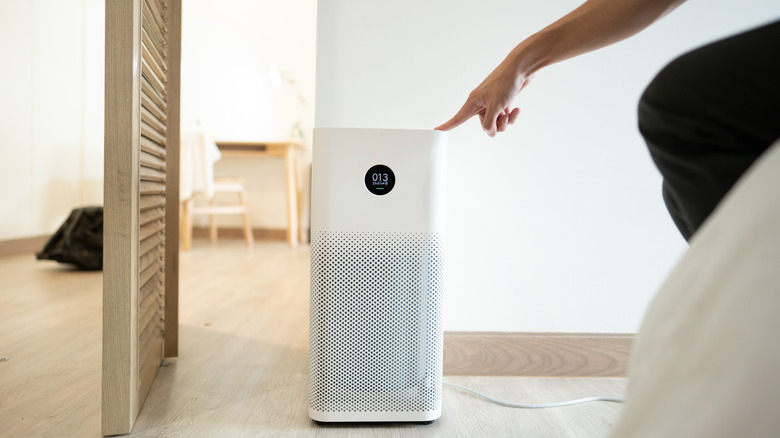 A person turning on an air purifier in a home