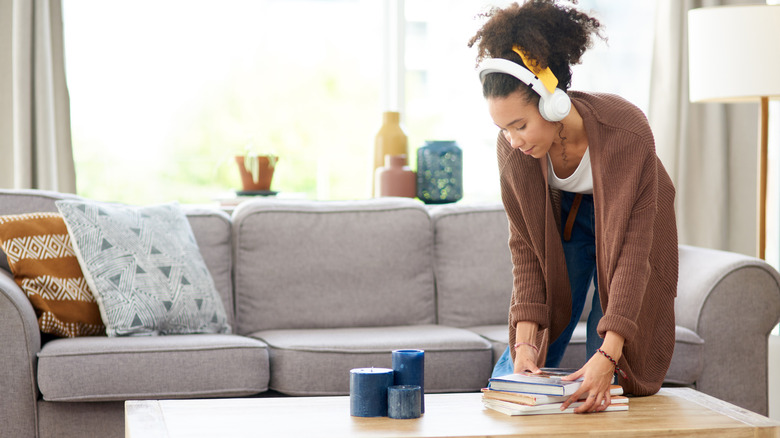 Woman wearing headphones straightening up coffee table books