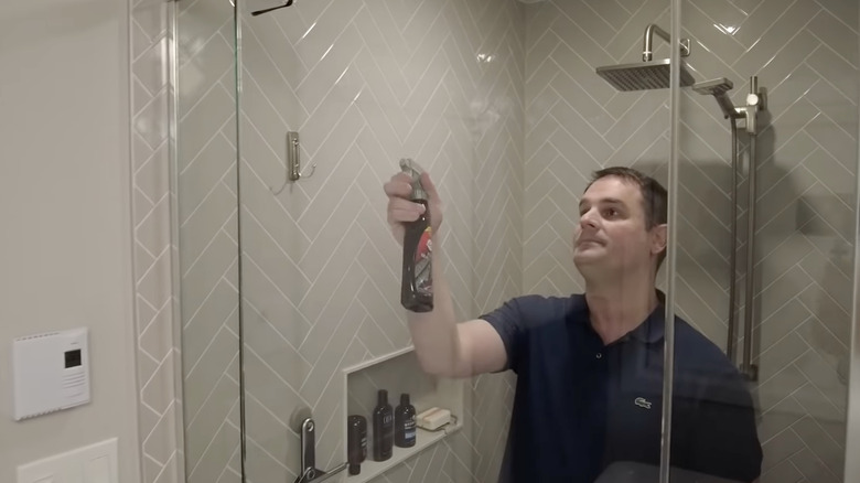 man applying spray wax to shower door