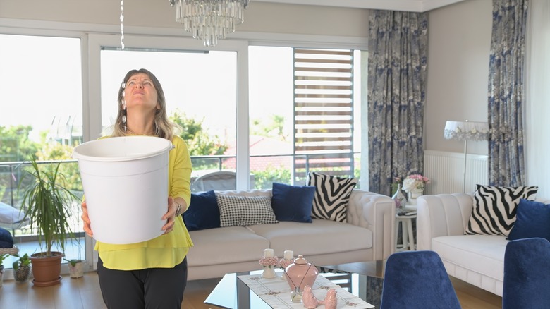 woman with bucket under leak