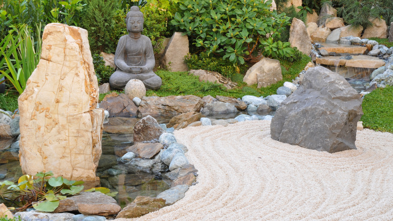 A buddha statue as a traditional ornament with raked sand in a Japanese garden