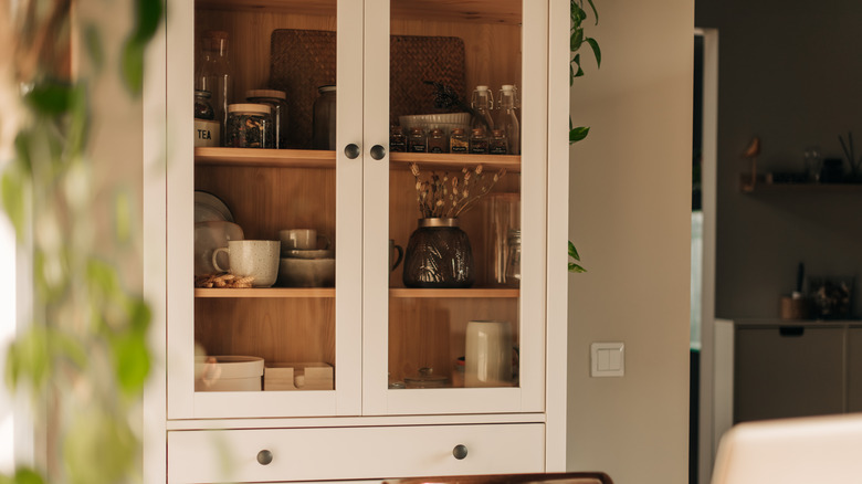 A white kitchen cabinet with lots of kitchenware