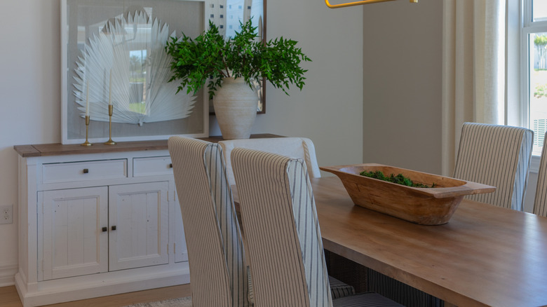 A wooden white sideboard in a dining area with decor on its tabletop