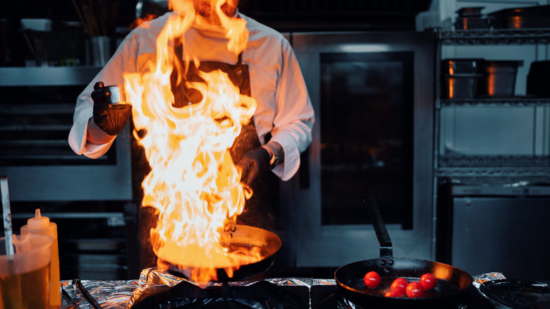 Chef flambéing with oil on fire in a pan