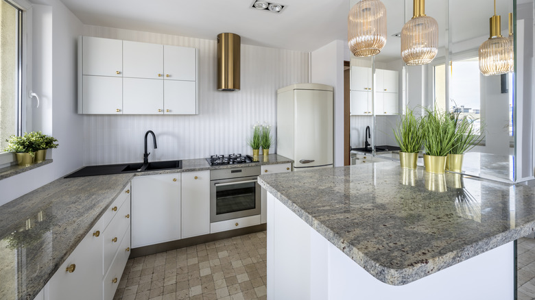 Kitchen countertop and island with white cabinets and pendant lights