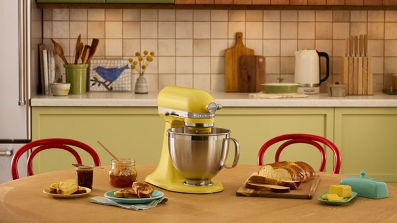 butter yellow Kitchenaid stand mixer surrounded by food in a kitchen