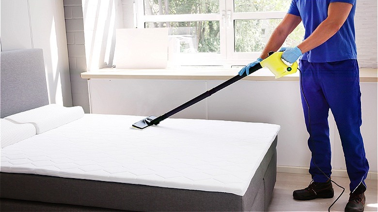 Person steam cleaning mattress