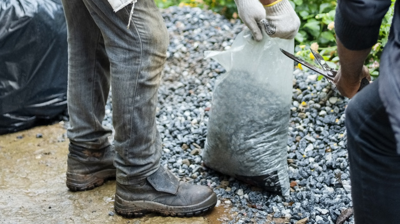 Men cutting bag of gravel