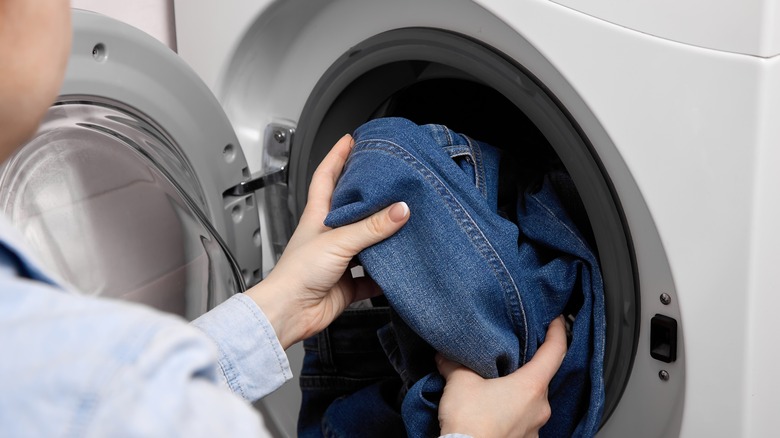 person placing jeans in washer