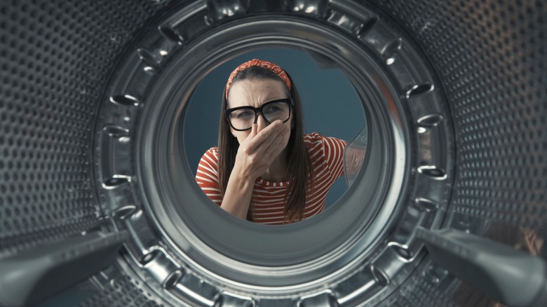 Woman covering nose looking in washer