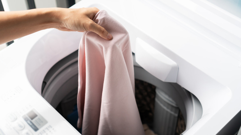 woman putting clothes in washing machine