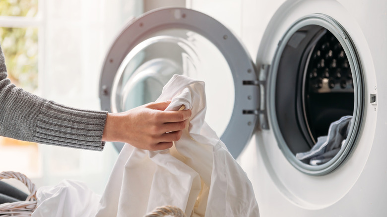 A person placing laundry into their washing machine