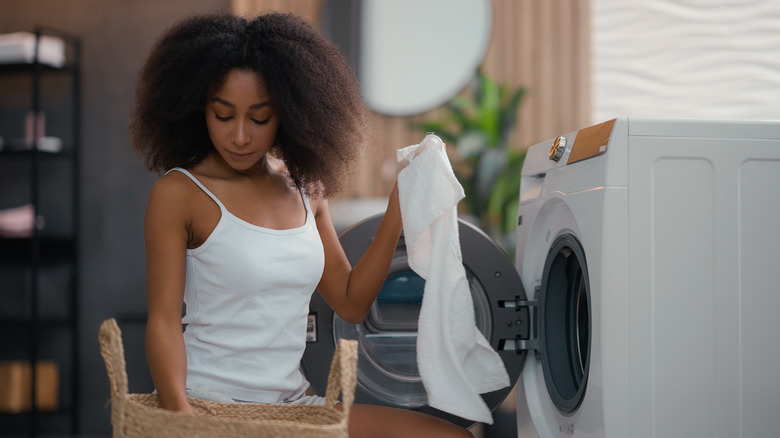 Person holding white towel in front of a washing machine