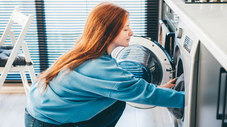 A person fluffing laundry in the washer