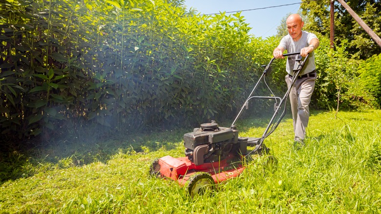 Man mowing with a lawn mower that's smoking