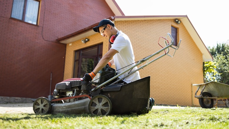 Man tinkering with his lawn mower