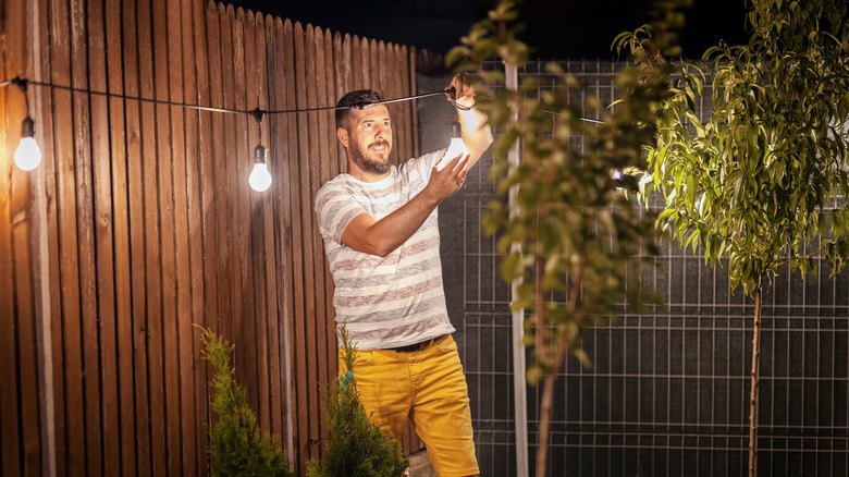 man fixing bulbs on patio