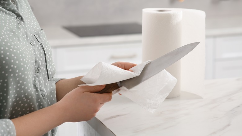 Hands wiping knife with paper towel