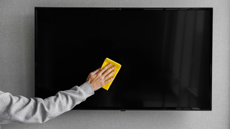 person wiping tv screen