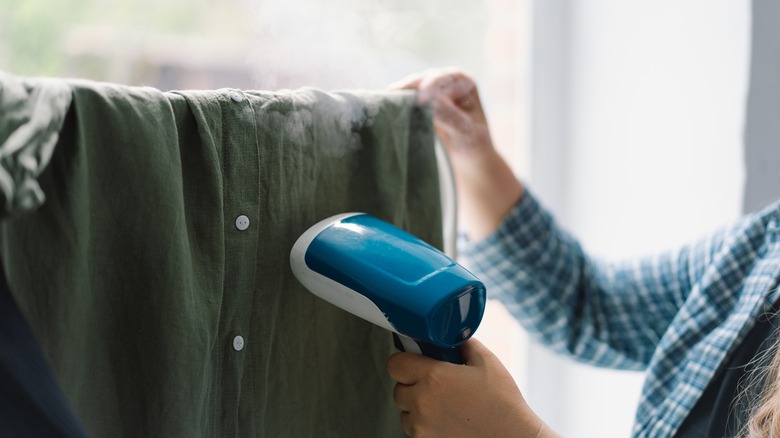 Using handheld steamer on button-up shirt