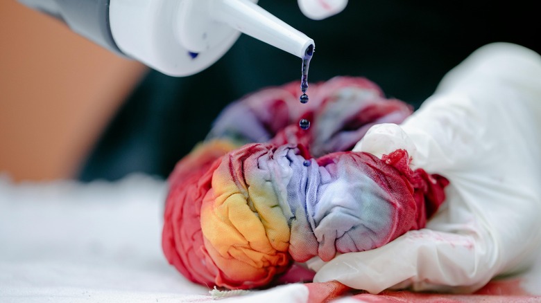 Tie-dye ink drips onto colorful fabric