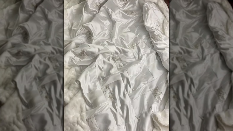 A white quilt with decorative details made from wedding dress