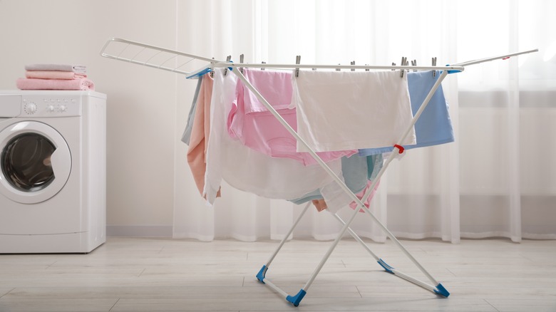 Clothes hanging on white drying rack in laundry room